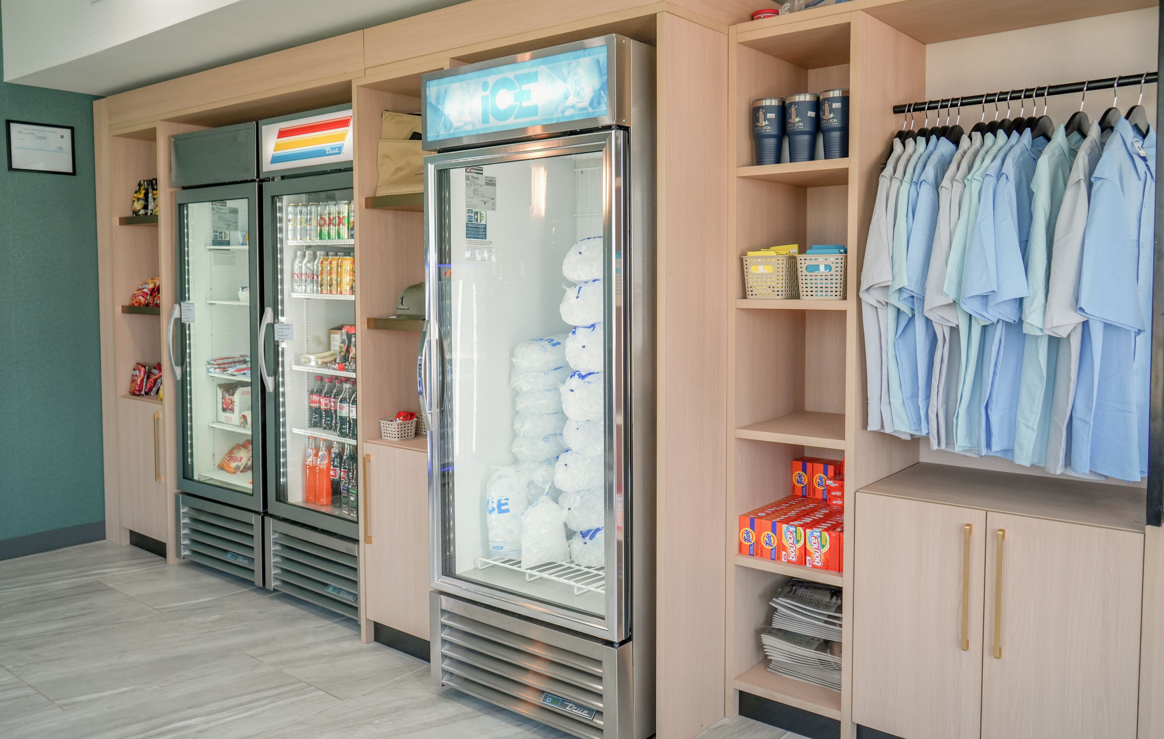 Et hotelværelse med minibar, køleskab, tøjstativ og hylder med diverse genstande.