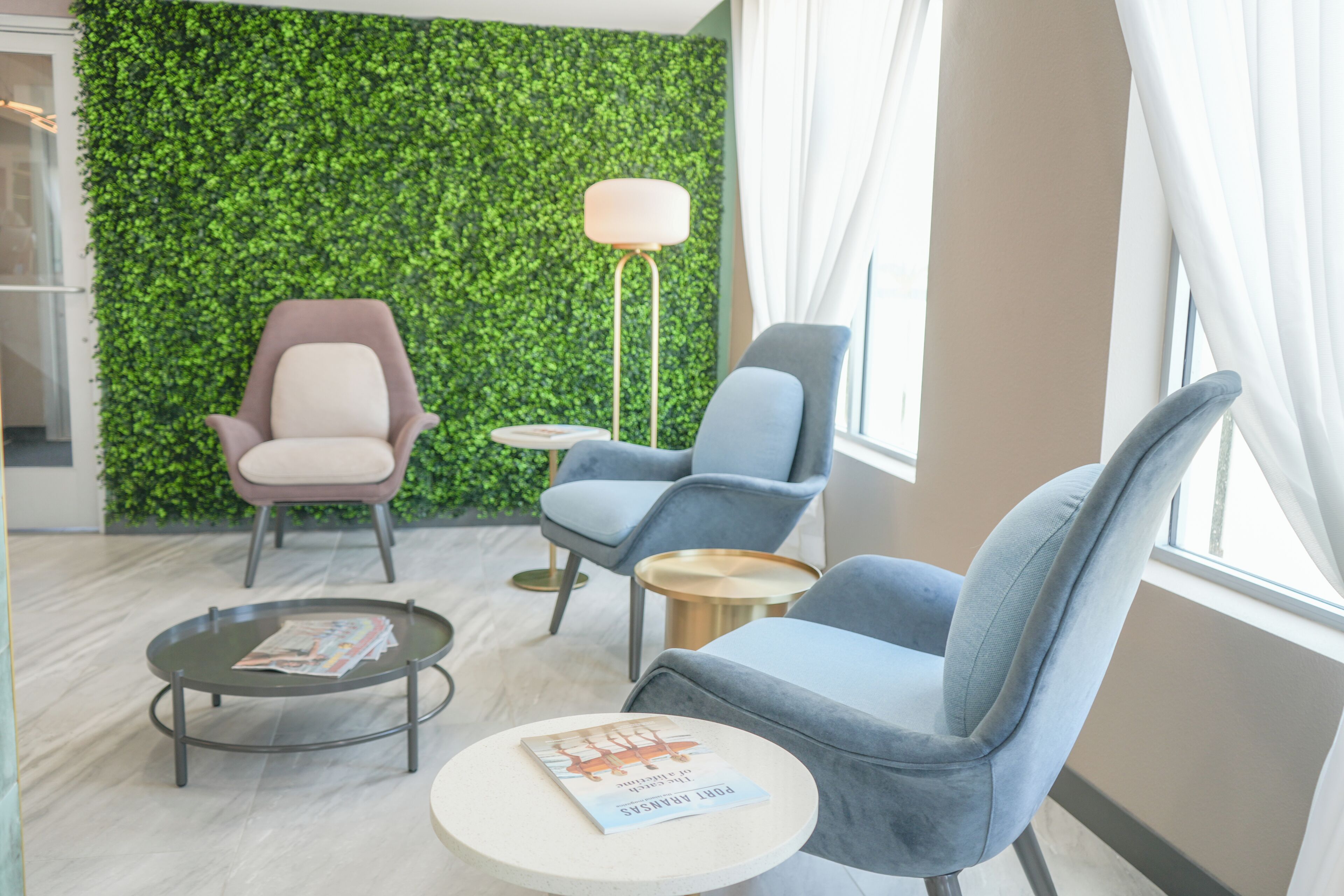 Un espace de détente moderne avec un mur végétal, deux fauteuils, une table basse ronde et un lampadaire.
