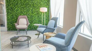 Un espace de détente moderne avec un mur végétal, deux fauteuils, une table basse ronde et un lampadaire.