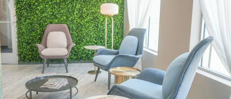Un espace de détente moderne avec un mur végétal, deux fauteuils, une table basse ronde et un lampadaire.