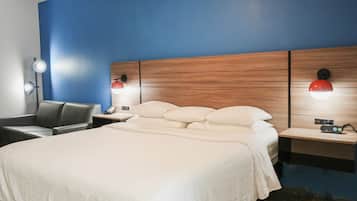 Une chambre d’hôtel avec un grand lit, deux tables de chevet avec des lampes, une chaise et une tête de lit en bois.