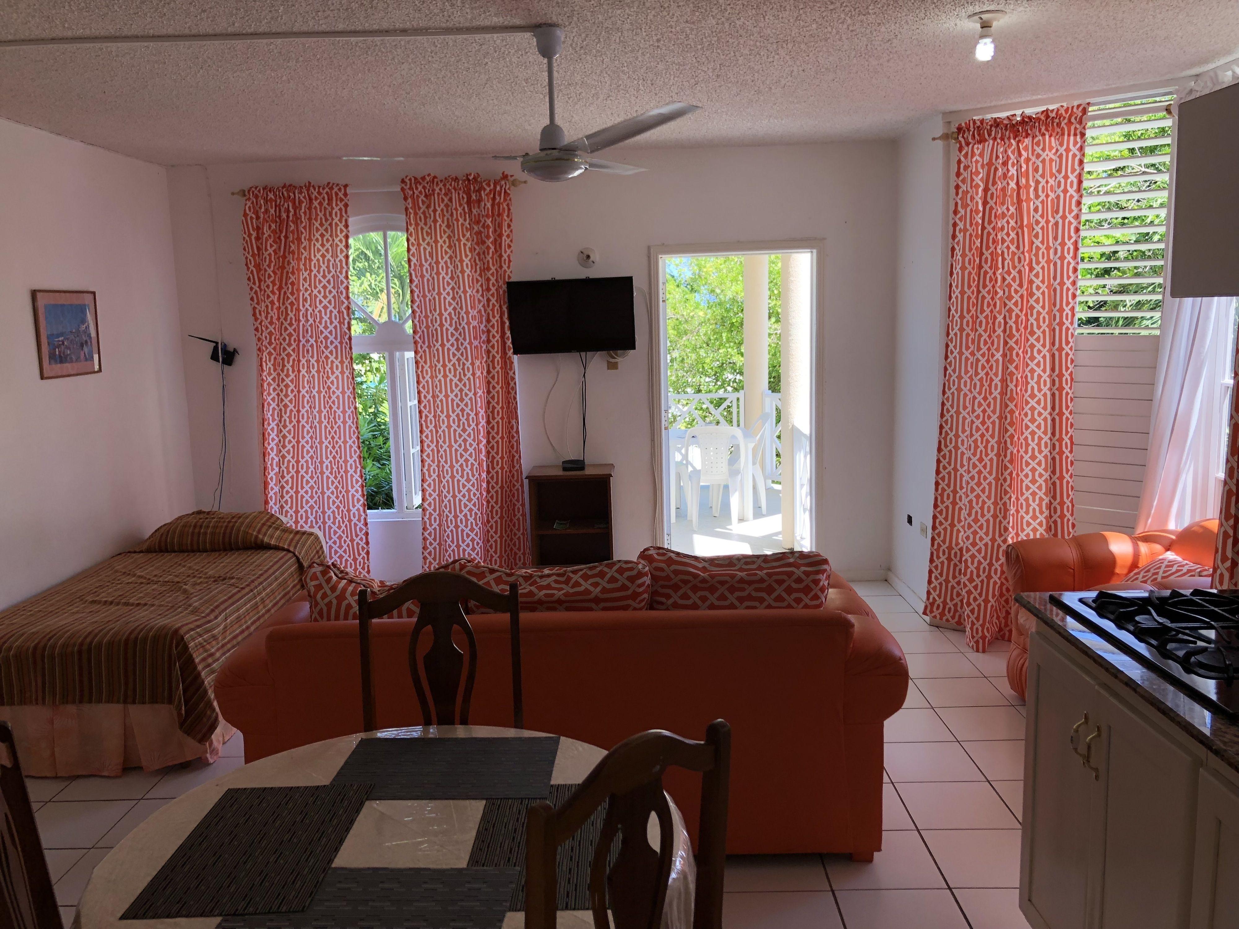 A compact living space with a bed, sofa, dining table, and kitchenette.