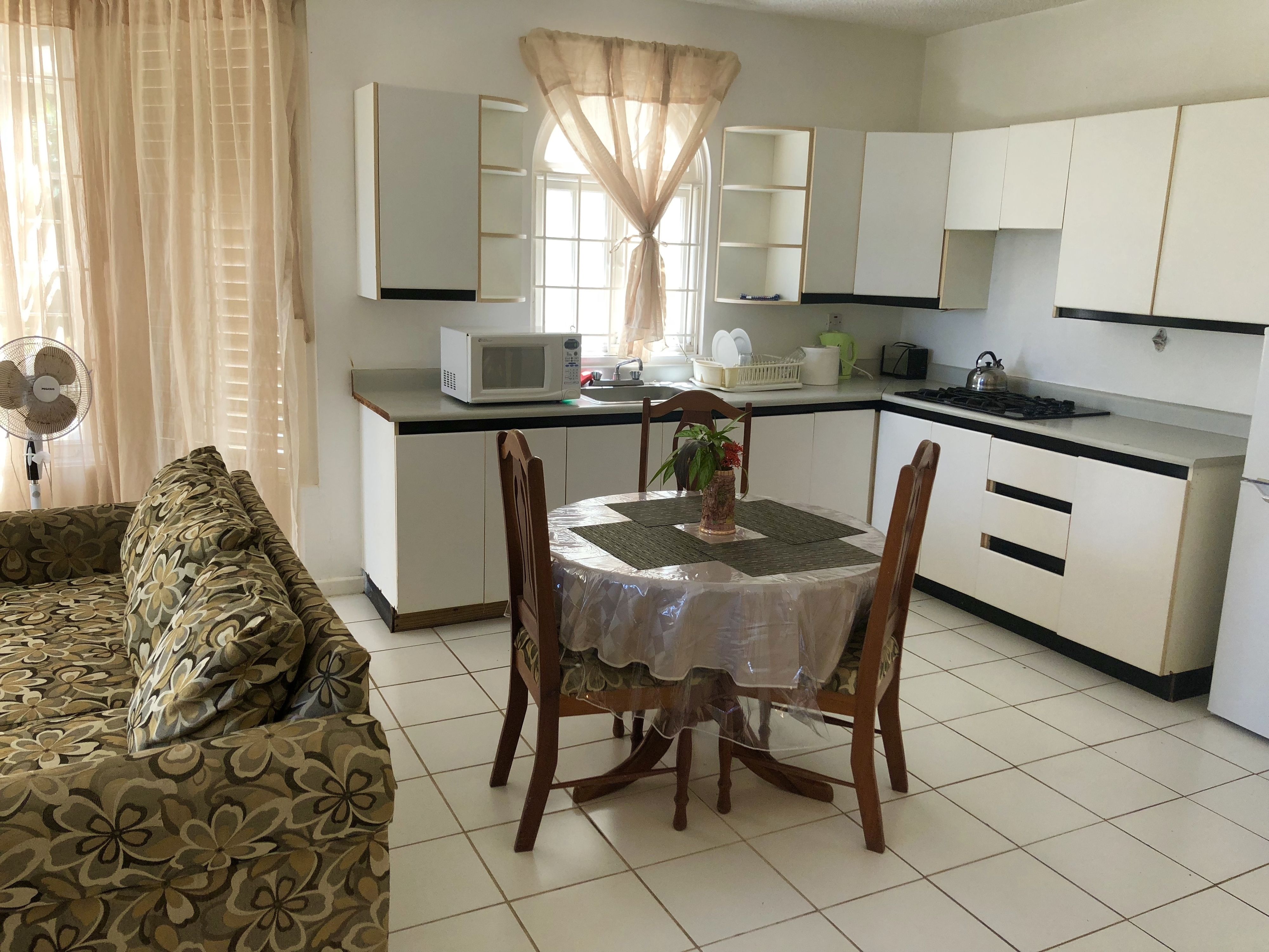 A modern kitchen with white cabinets, a microwave, and a dining table with chairs.