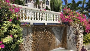 A stone water feature with a decorative white fence and lush greenery.