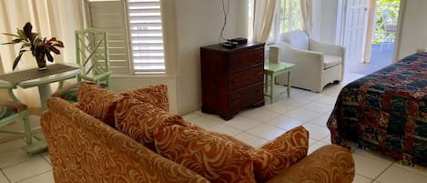 A hotel room with a sofa, a TV, a dresser, a chair, and a bed.