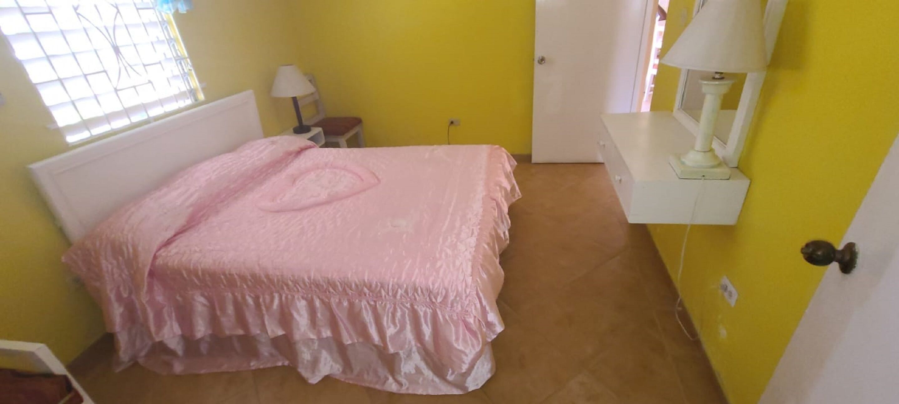 Ein Zimmer mit Bett, Stuhl, Lampe und einer Tür.