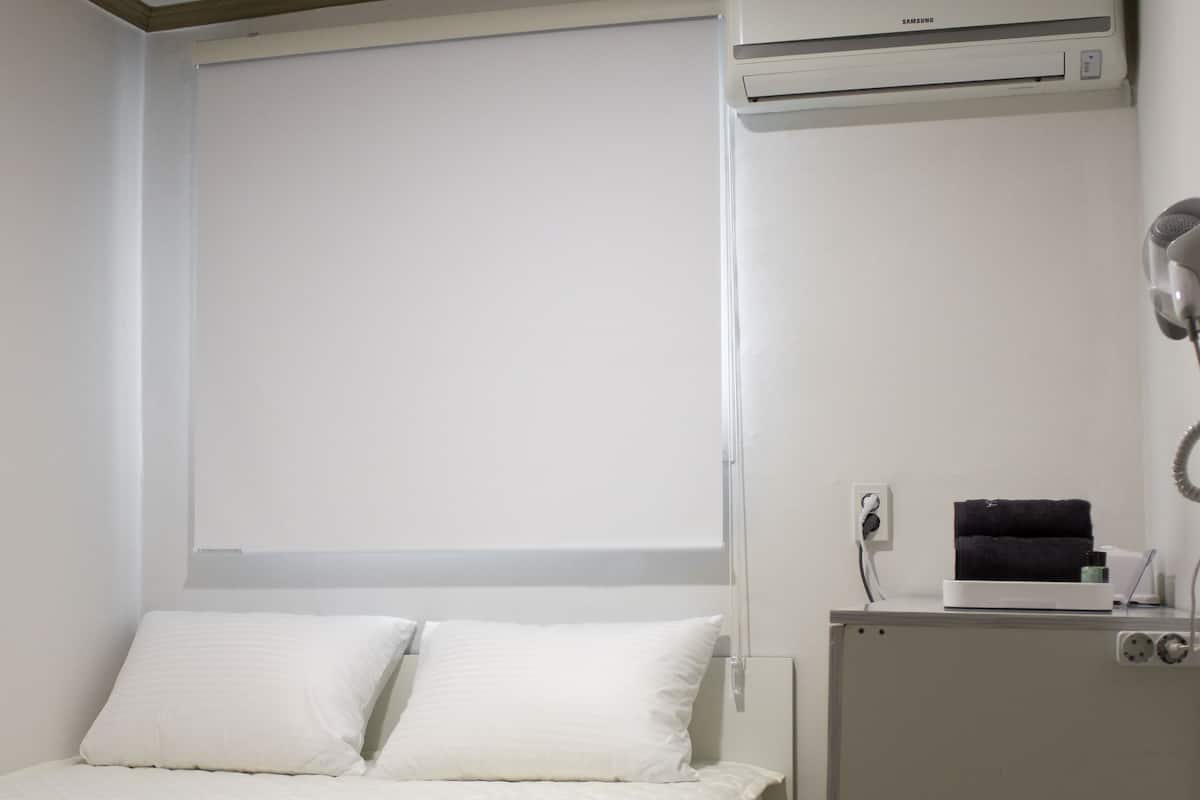 Une chambre d’hôtel équipée d’un lit, d’un mini-réfrigérateur, d’une poubelle et d’un appareil de climatisation.