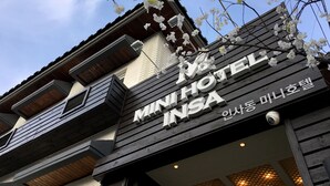 Une enseigne d’hôtel portant le nom « MINI HOTEL INSA » et une caméra de surveillance.