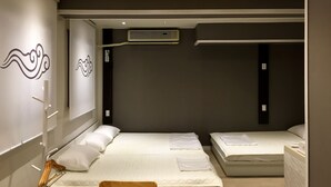 Une chambre d’hôtel avec deux lits, une armoire, un miroir et un climatiseur fixé au mur.