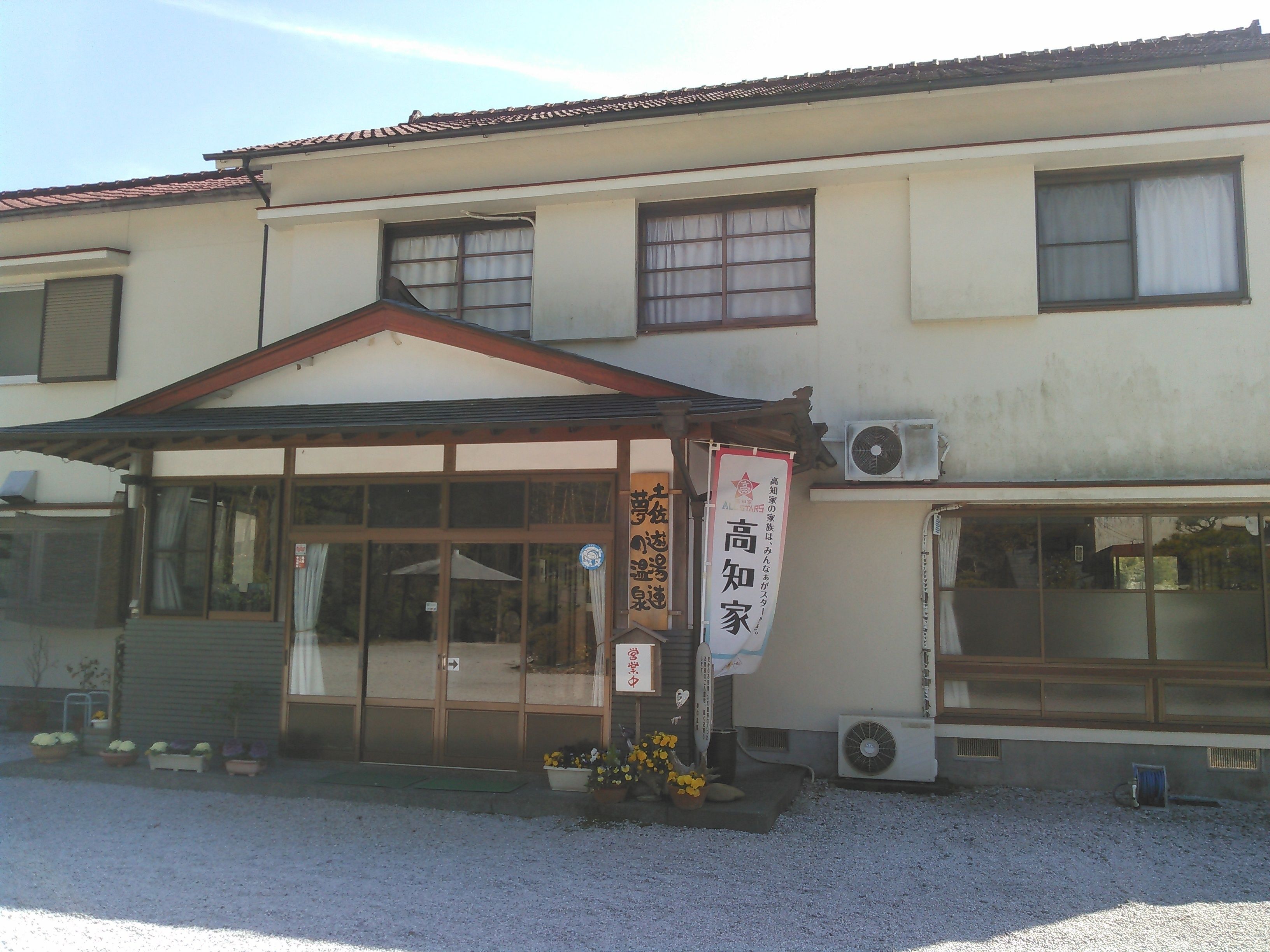 A building with a traditional architectural style, featuring a tiled roof and a covered entrance area.