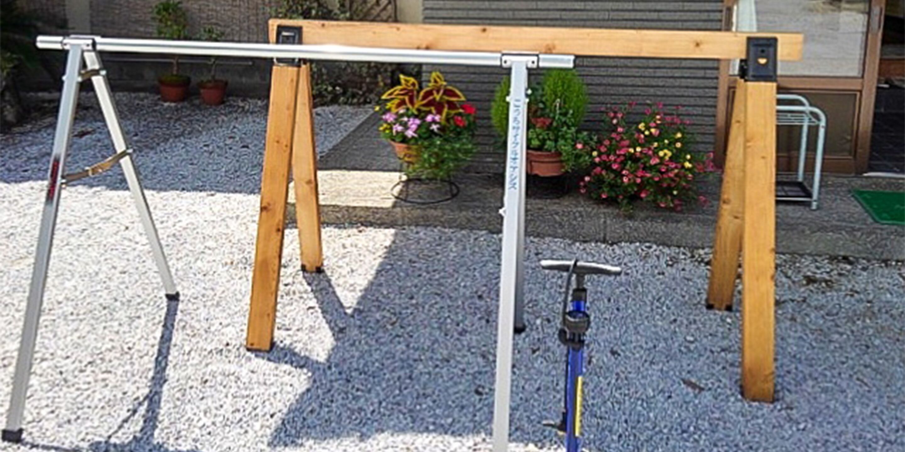 Una mesa de madera con estructura metálica, rodeada de macetas y grava.