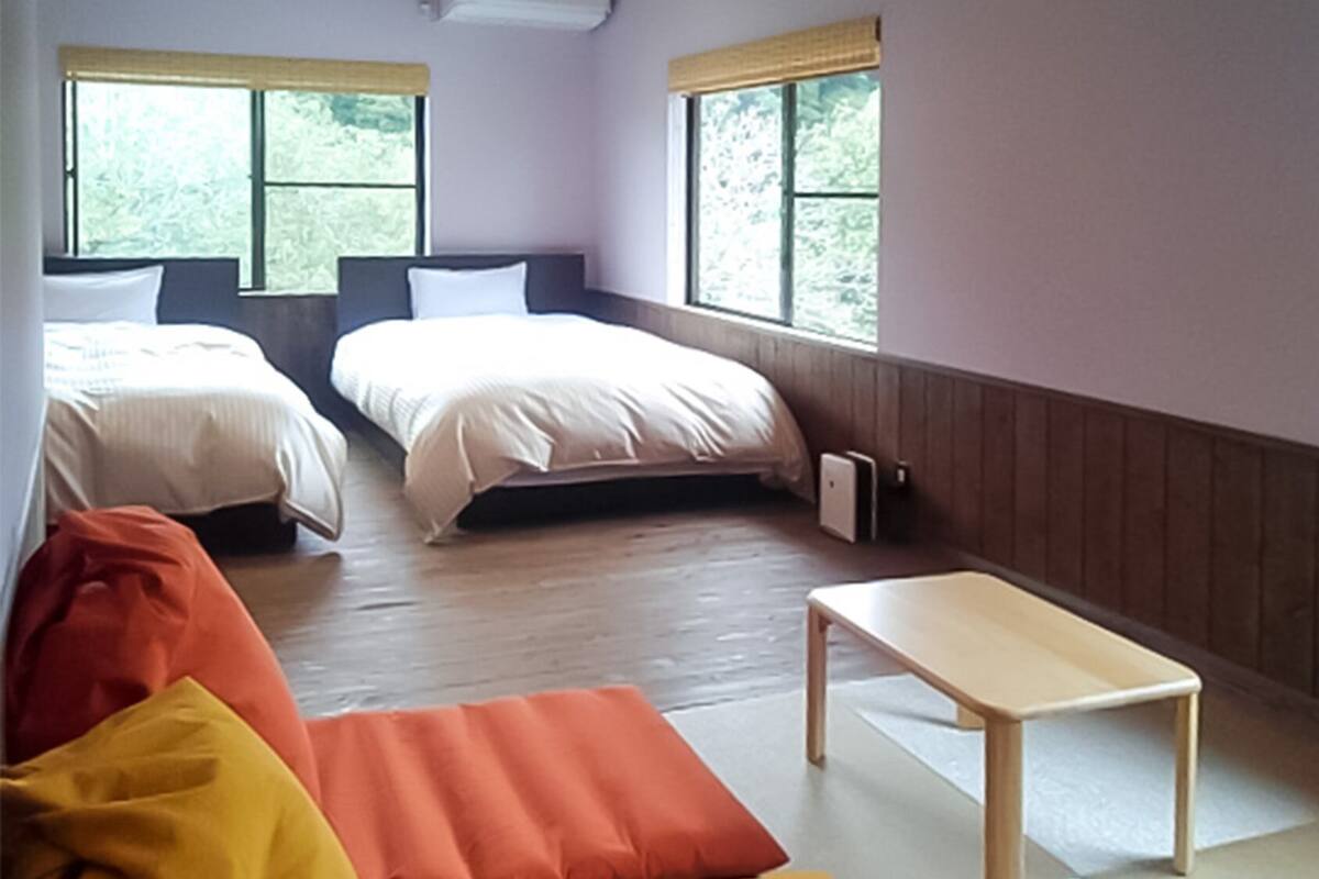 Une chambre avec deux lits, une petite table et un canapé.