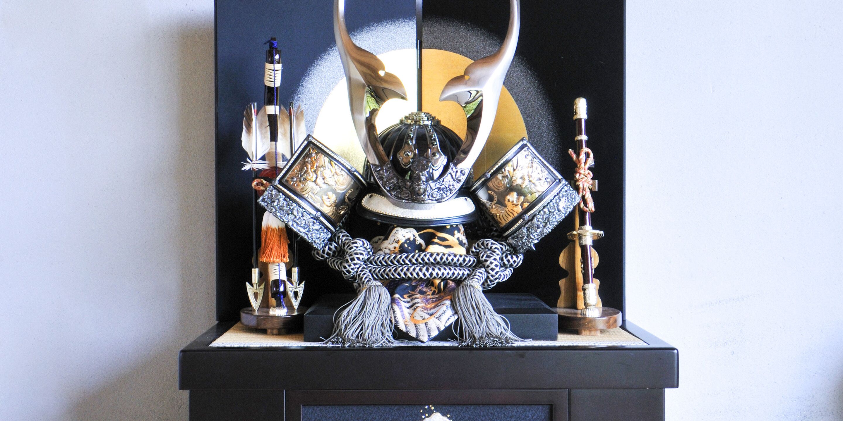 Une exposition d’objets d’art japonais traditionnels, comprenant une épée, un bâton cérémoniel et un bouclier décoratif.