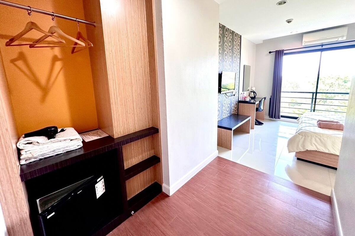 A hotel room with a bed, a desk, a TV, and a bathroom.