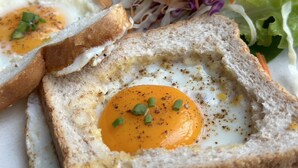 Un plato de desayuno con tostadas, un huevo frito y una ensalada.