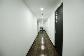 A long, narrow hallway with white walls and a shiny wooden floor. - Stayan - Hostel (Busan)
