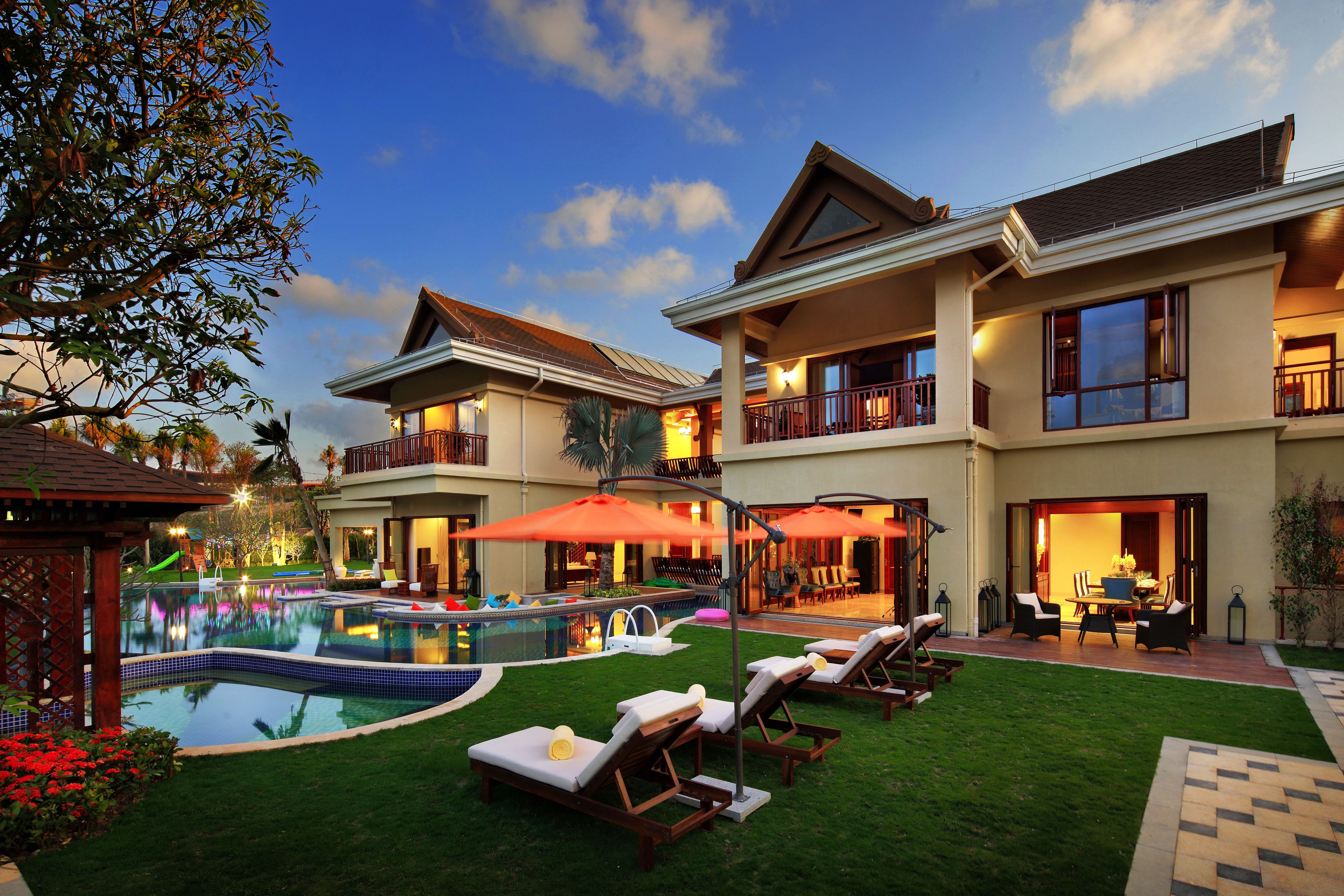 A large house with a swimming pool, outdoor seating, and a well-maintained lawn.