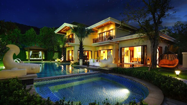 A two-story resort with a swimming pool, outdoor seating, and a gazebo.