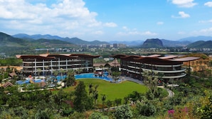 A resort with multiple buildings, a swimming pool, and lush greenery.