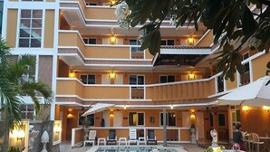 A multi-story hotel with a pool area, outdoor seating, and multiple balconies.