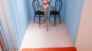 A small room with a round table and two chairs, a vase with flowers, and a red carpet.