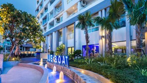 A hotel with a pool area, palm trees, and a sign that reads "BLUE BOAT". - Blue Boat Hotel JC (Pattaya)