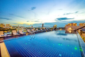 A rooftop infinity pool with lounge chairs and a city view at dusk. - Blue Boat Hotel Pattaya (Pattaya)