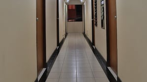 Um corredor longo e estreito com portas de ambos os lados, dando acesso a quartos.