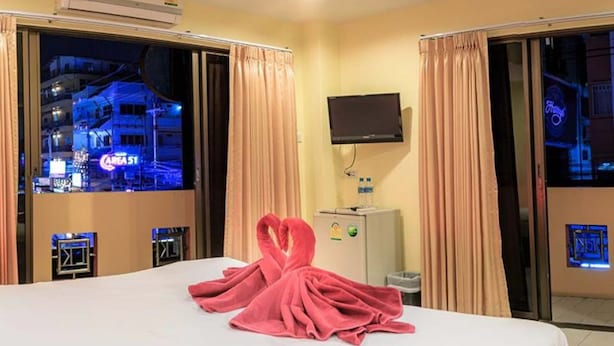Quarto de hotel com uma cama, uma TV de tela plana na parede e vista para a cidade pela janela.