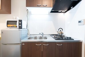 A compact kitchen with a microwave, refrigerator, sink, and stove. - MUSUBI KYOTO Higashiyama Gojo (Kyoto)