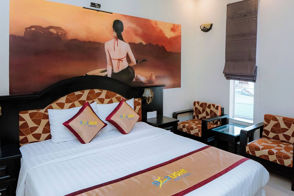 Habitación de hotel con una cama grande, dos sillones, una mesita y un cuadro en la pared.