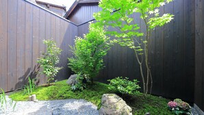 Un giardino con recinzione in legno, rocce e diverse piante.