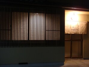 Ein Gebäude mit vertikalen Jalousien, einem Schild mit japanischen Schriftzeichen und einer Leuchte.