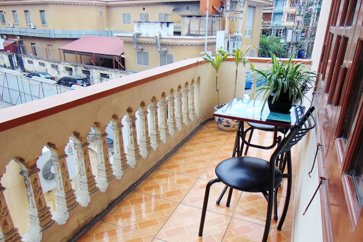 Un balcon avec un sol carrelé, une table avec des chaises et une plante en pot.