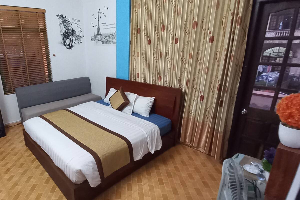 Une chambre à coucher comprenant un lit, une armoire, une fenêtre avec des stores et une porte avec des rideaux.