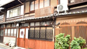 A traditional Japanese building with a wooden exterior, a black metal gate, and a small air conditioning unit on the side. - KYOMACHIYA NO YADO 794inn KIYOMIZUGOJO (Kyoto)