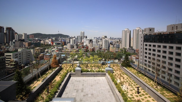 Una terraza en la azotea con vistas a un paisaje urbano, incluyendo varios edificios y una colina distante.