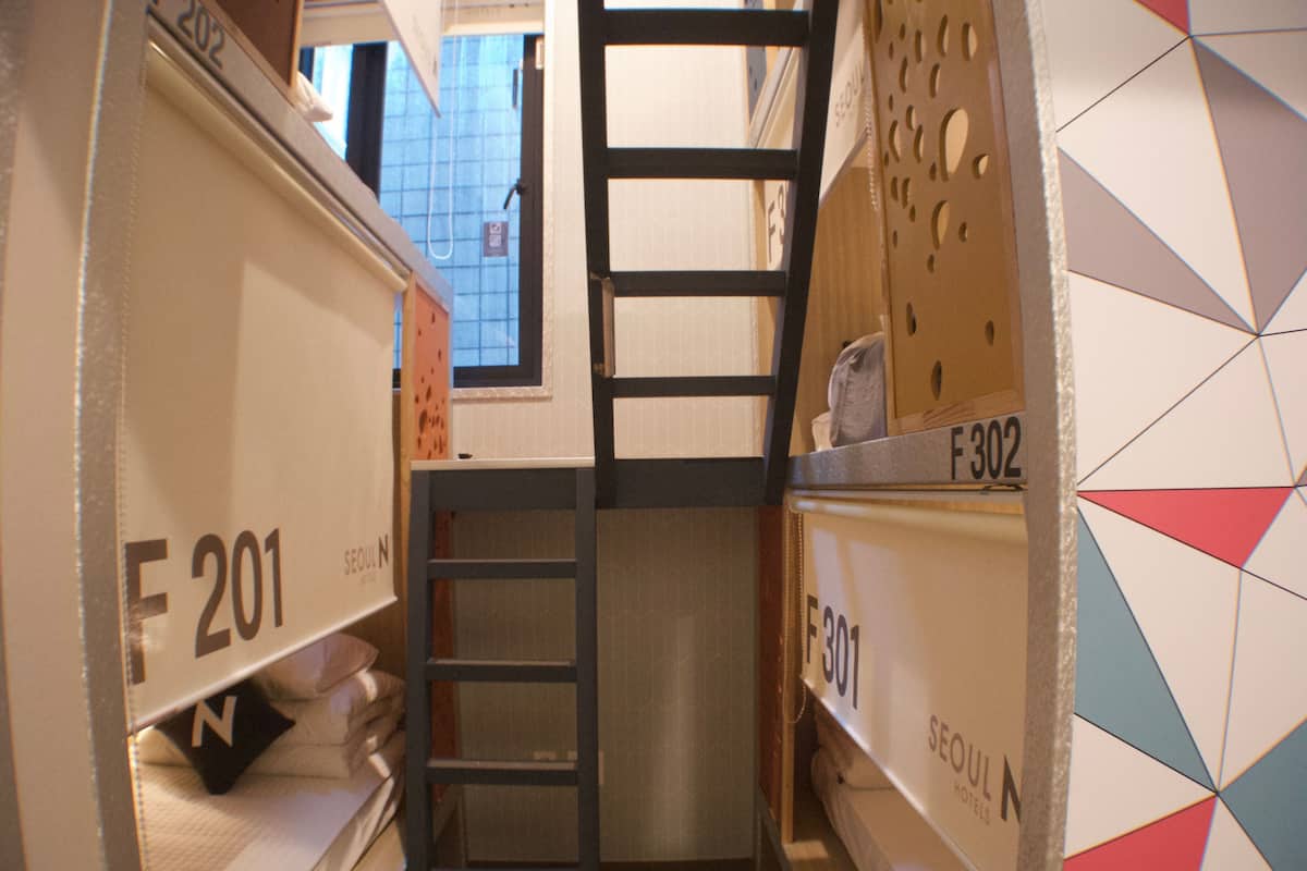 Un couloir étroit, doté de rangements étiquetés F201 et F302, qui mène à une porte.