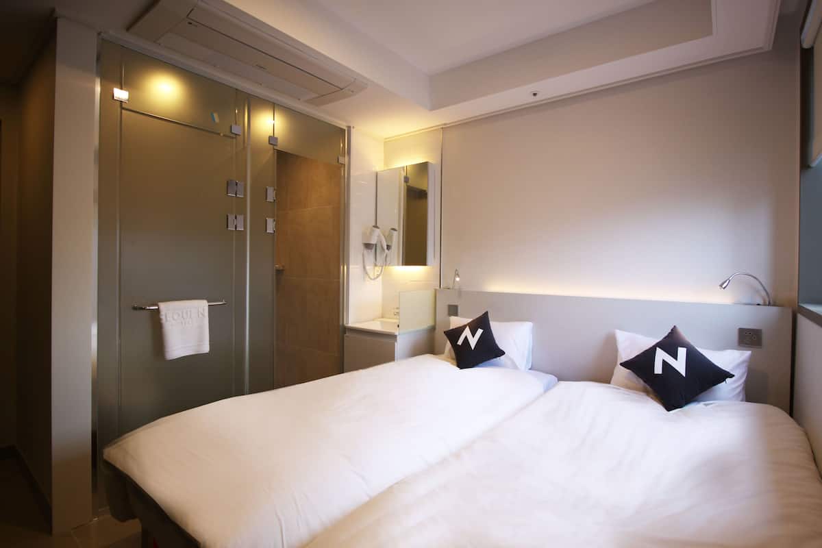 Une chambre d’hôtel avec un grand lit, une salle de bain avec un miroir et une armoire.