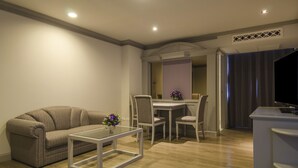A modern living room with a sofa, a glass coffee table, and a dining area with chairs and a table. - imm hotel Ladprao Bangkapi Bangkok (Bangkok)