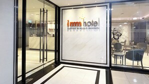 A modern hotel entrance with a glass facade, a reception desk, and seating area visible through the glass. - imm hotel Ladprao Bangkapi Bangkok (Bangkok)