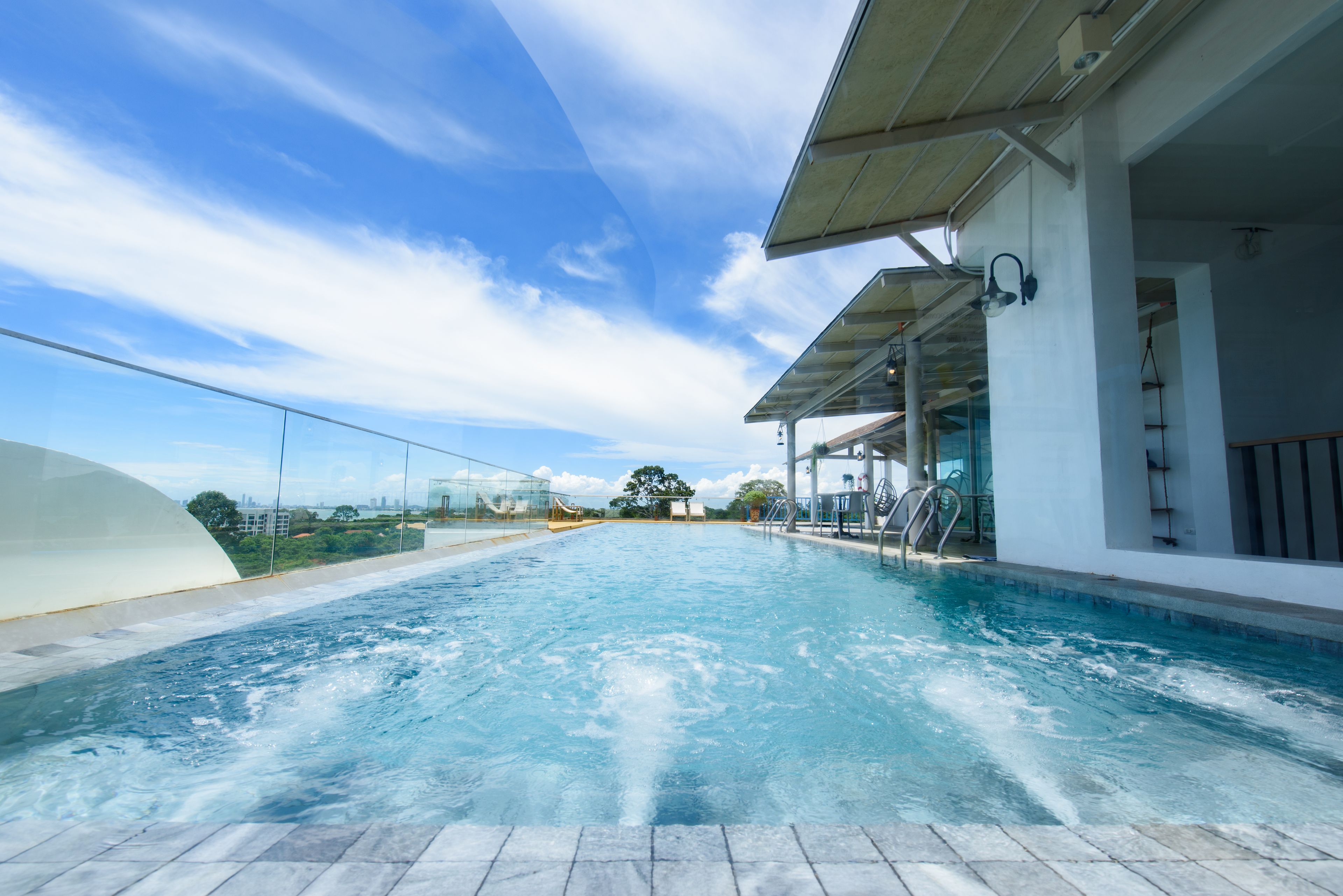 Une piscine sur le toit, avec une eau d’un bleu cristallin, entourée d’une balustrade en verre et dotée d’une architecture moderne.