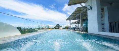 A rooftop pool with clear blue water, surrounded by a glass balustrade and a modern architectural design.