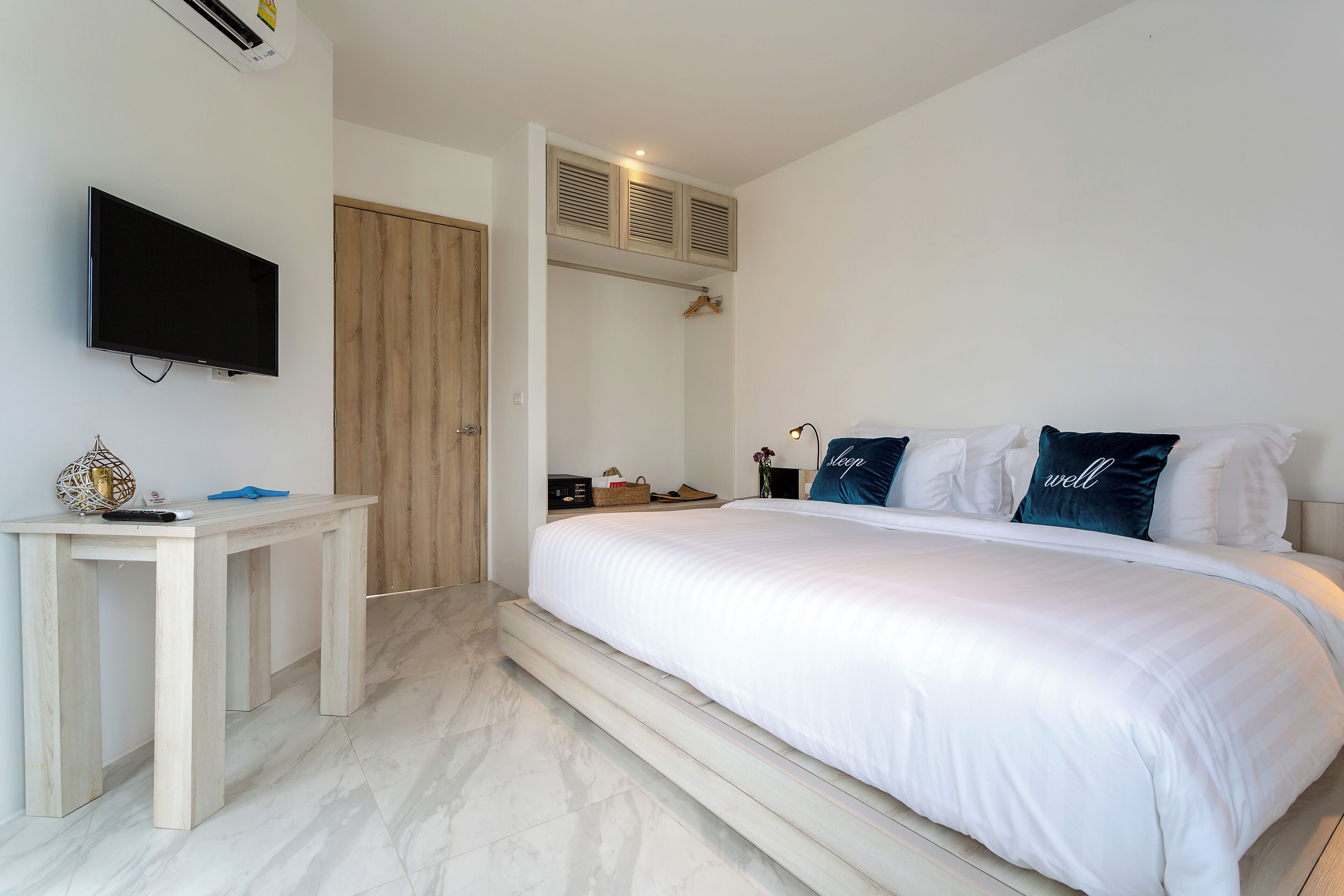 A bedroom with a bed, a TV, a desk, and a wardrobe.