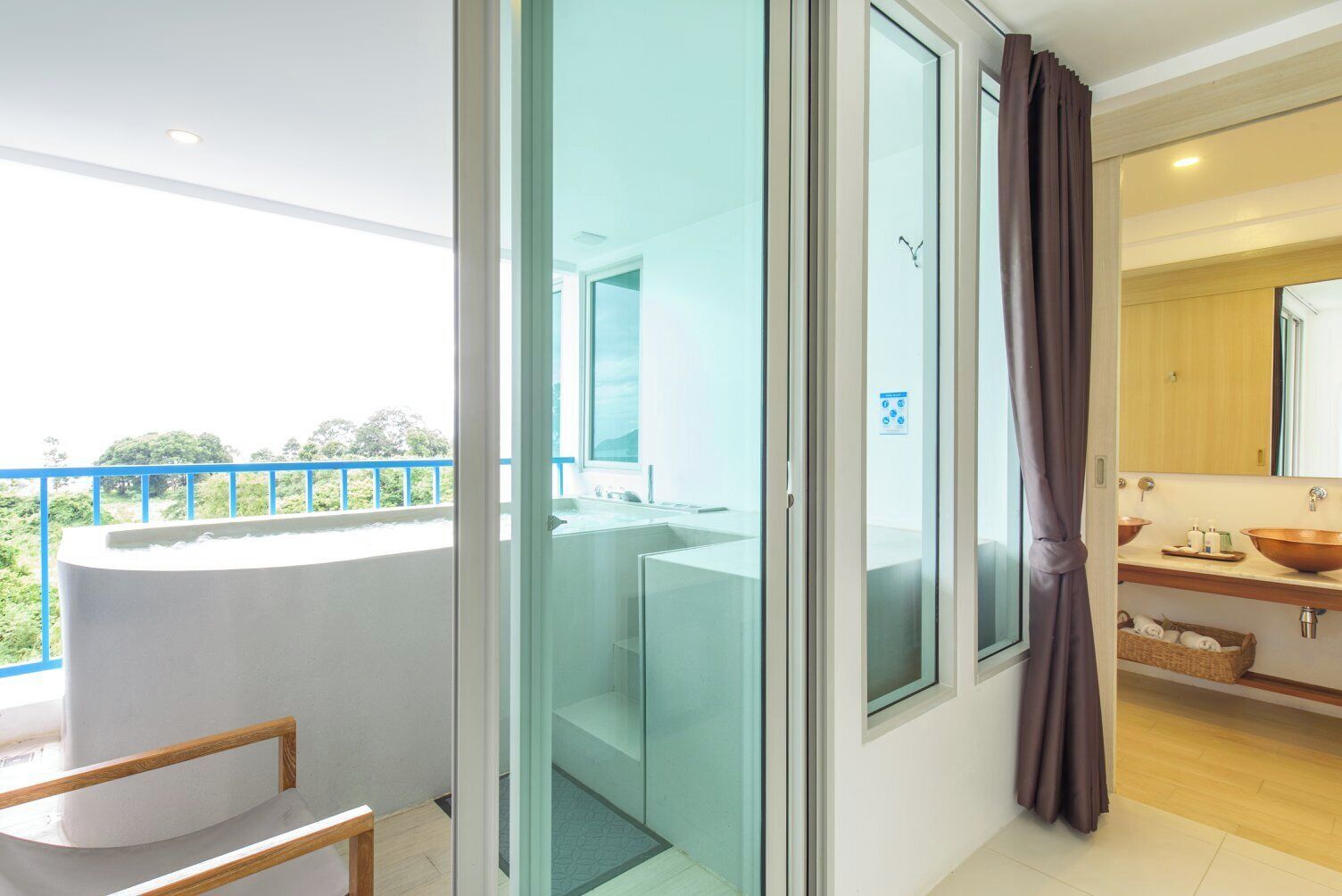 A modern bathroom with a glass shower enclosure, a large mirror, and a wooden vanity with a copper basin.