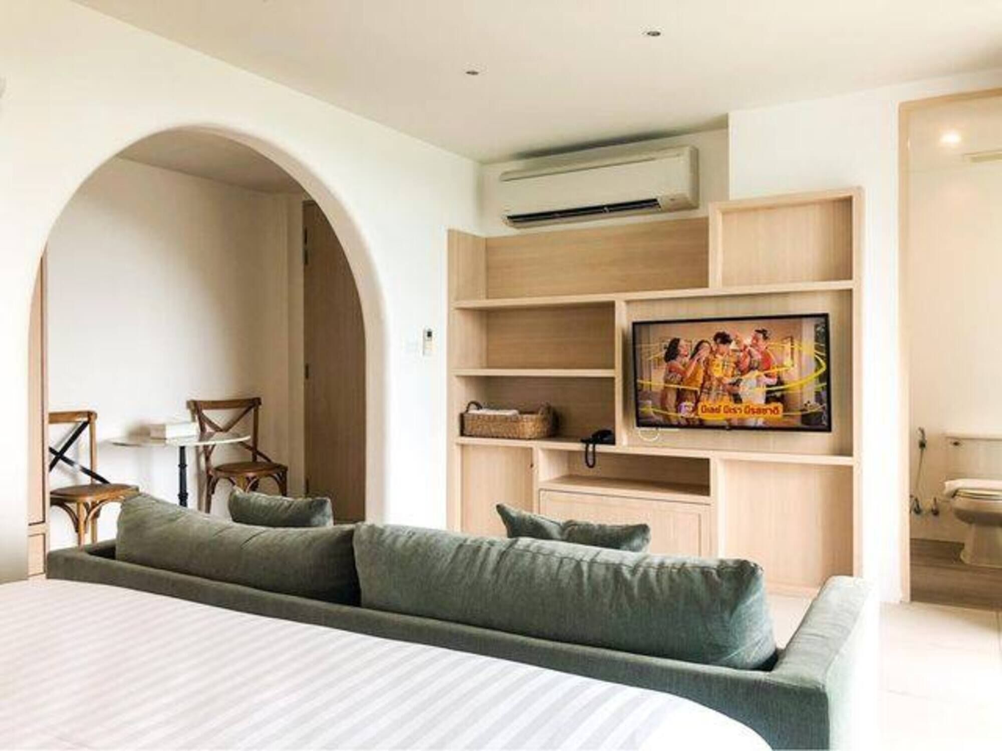 Een moderne hotelkamer met een groot bed, een ingebouwde televisie, een bank en een houten tv-meubel.
