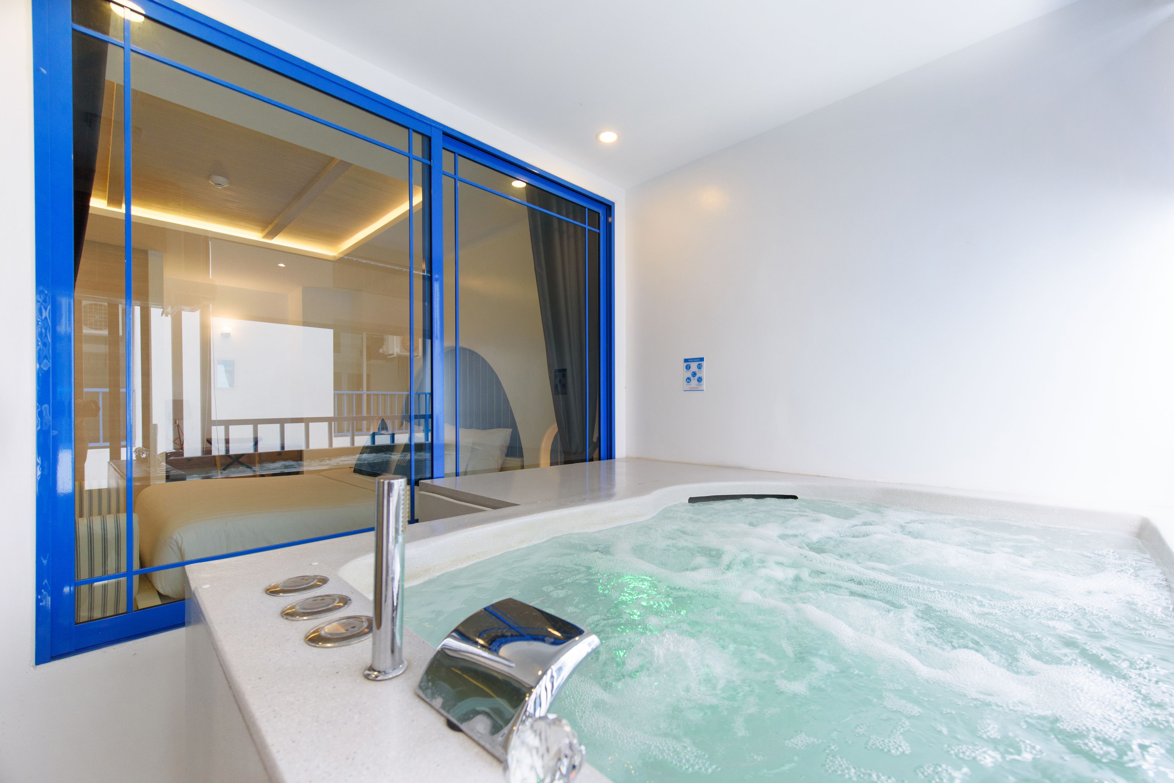 Une salle de bain moderne dotée d’une grande baignoire, d’une douche à l’italienne et d’un lit visible avec un oreiller à rayures.