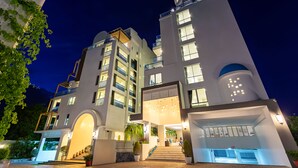 Ein modernes Hotel mit mehreren Etagen, einem zentralen Eingang mit Stufen und einer überdachten Außenbereich.