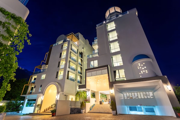 Un hôtel moderne à plusieurs étages, doté d’une entrée principale avec des marches et d’un espace extérieur couvert.
