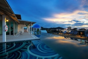 Une piscine sur le toit, dotée d’une structure en forme de dôme bleu, de chaises longues et d’une balustrade en verre.